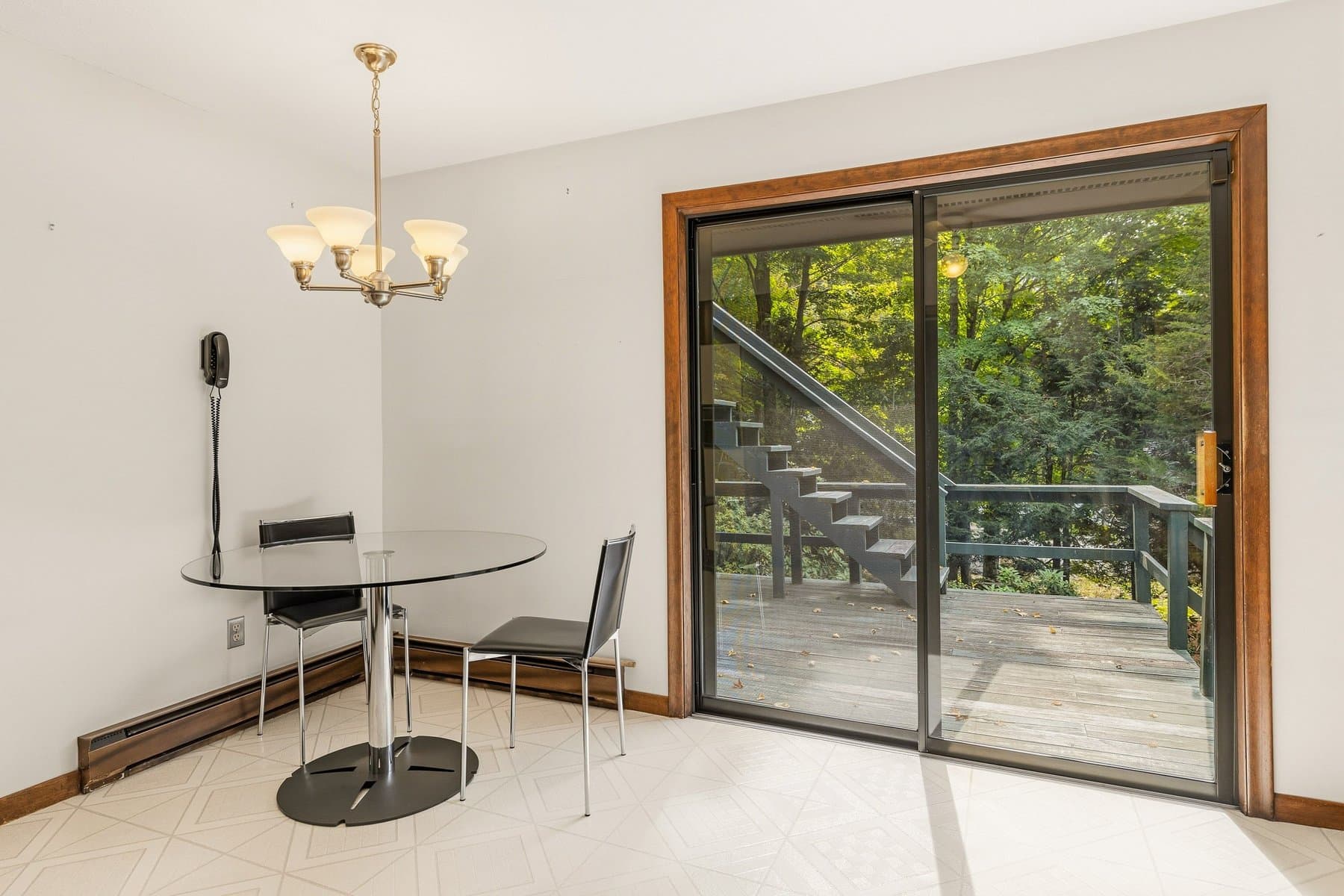 The dining nook in the kitchen with a chandelier and a slider out to the deck