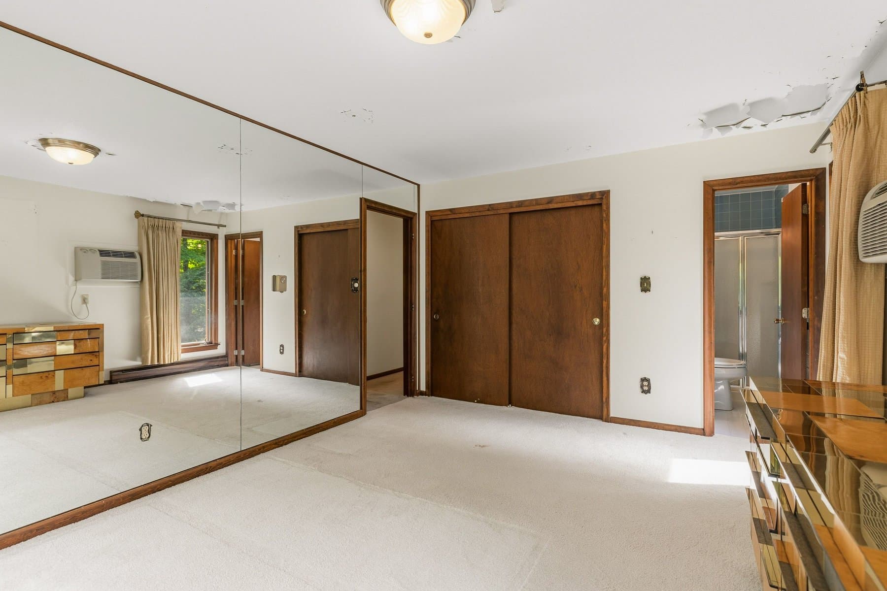The primary bedroom's mirrored wall, closet doors, and the door to its bath
