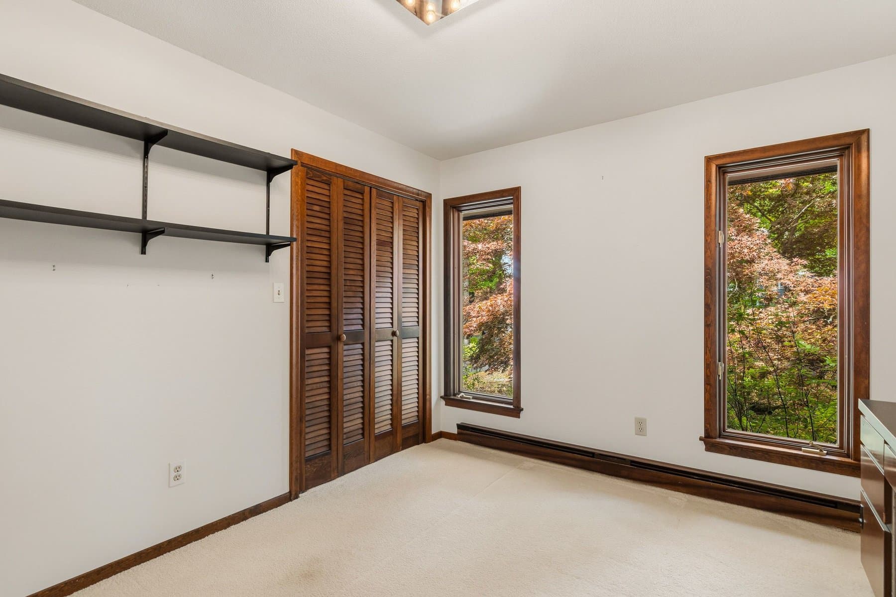 The second bedroom with louvered closet doors, 2 windows to the maples, and wall shelves