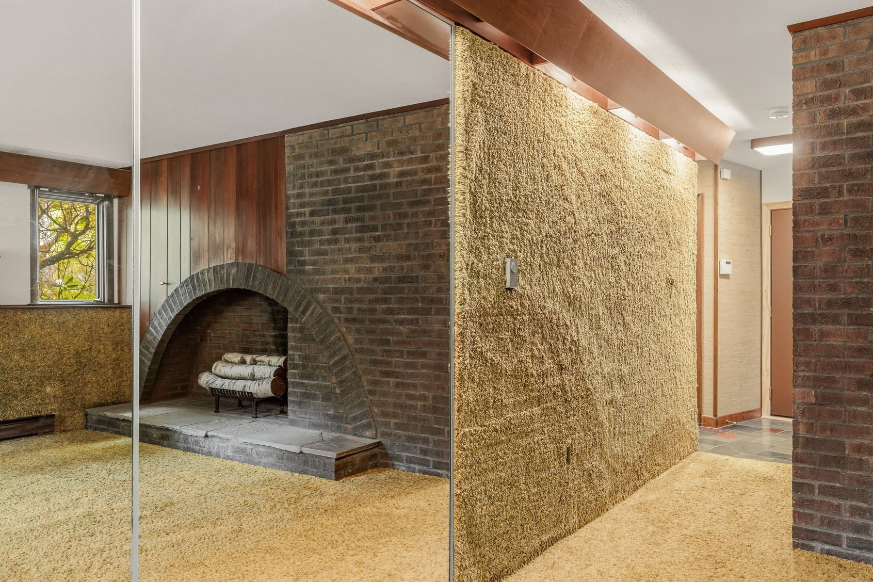 The lower-level hall past the arched fireplace, with the slate floor at the far end